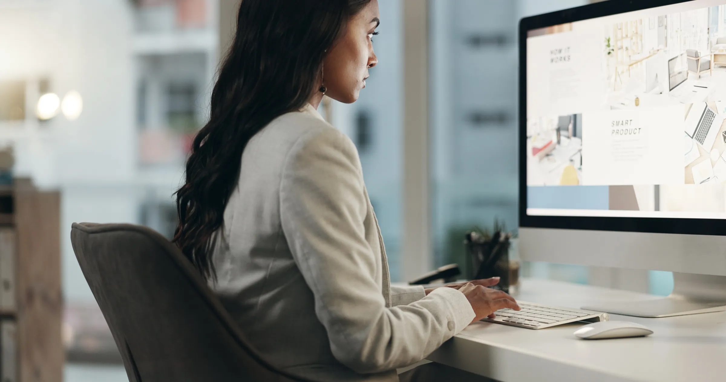 Designer lucrând la structura unei pagini web pe un monitor desktop, cu secțiunile paginii vizibile pe ecran